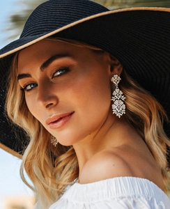 Detailed view of silver hollow flower tassel earrings on a model with warm lighting