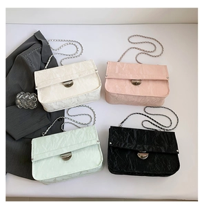 Flat lay of chic chain shoulder bags in white pink mint and black leather colors
