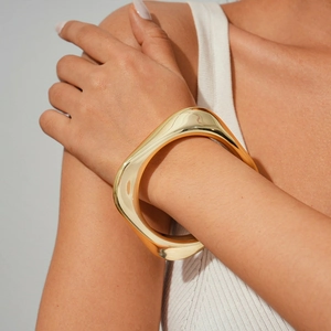 Close-up of golden irregular geometric bangle with organic sculptural design on wrist