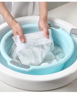 Blue plastic washbasin with gray non-slip handles for washing clothes in a bathroom sink