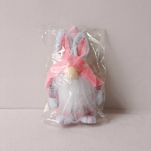 Detailed close-up of a pink Easter gnome doll with bunny ears in clear plastic packaging