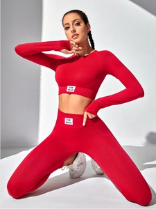 Close-up of red high-waist yoga leggings and long sleeve top with GYM WEAR woven label