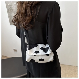 Mini crossbody bag with black and white cow print texture worn by model for daily style