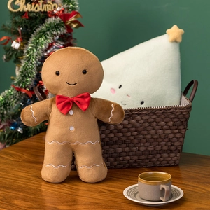 Close-up of a smiling brown gingerbread man plush toy in a cozy Christmas setting