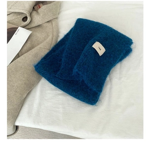 Detailed close-up of a soft blue wool-blend scarf featuring an egg logo fabric label