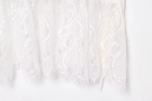 Close-up of intricate white floral lace trim with delicate eyelash fringe edges