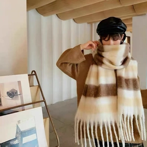 Close-up of thick beige and khaki plaid scarf featuring soft fringe and plush texture