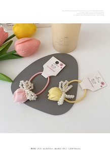 Detail of pink and yellow tulip hair ties with pearls on a decorative tray
