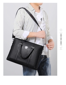 Close-up of the embossed leather texture and silver hardware on a black business bag