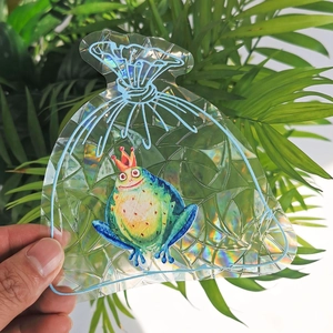 Detailed close-up of a holographic frog suncatcher sticker with rainbow prism reflections
