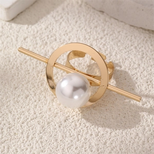 Close-up of golden geometric open ring featuring a large white pearl on a stone surface