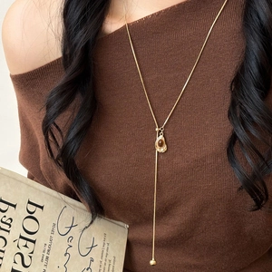 Detailed view of a gold Y-shaped necklace featuring an amber resin heart pendant on model