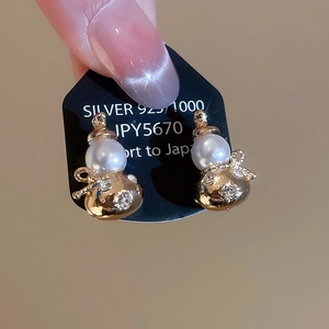 Macro shot of gold gourd-shaped pearl earrings with sparkling crystal accents