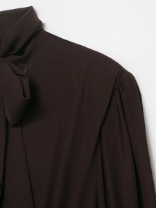 Detail of dark brown chiffon blouse featuring a tie-neck bow and pleated shoulder seams