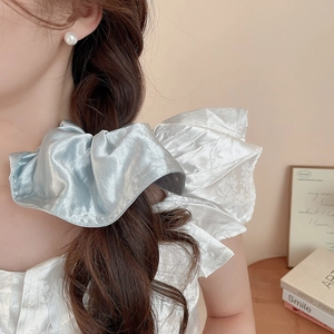 Detail of blue satin floral scrunchie with a glossy texture on a minimalist background
