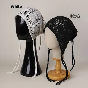 Détail de bonnets au crochet ajouré en blanc et noir avec rubans et motifs délicats