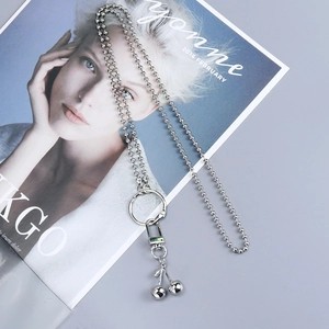 Detail of silver cherry pendant and bead chain accessory on a fashion magazine