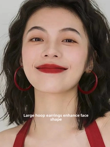 Close-up of model wearing large matte red circular hoop earrings with minimalist style