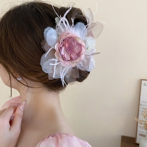 Détail de la pince à cheveux fleur en tissu rose avec plumes blanches sur chignon