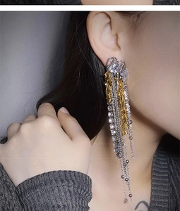 Close-up of golden tassel earrings featuring zircon inlay and wheat spike design