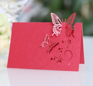 Close-up of red laser-cut butterfly place card with intricate floral scroll pattern