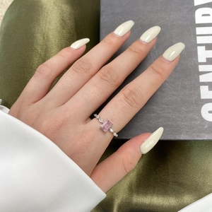 Macro view of a refined silver ring featuring a rectangular pink gemstone and accent diamonds