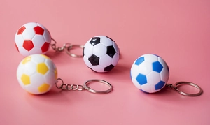 Gros plan de mini porte-clés football colorés en rouge, noir, bleu et jaune sur fond rose