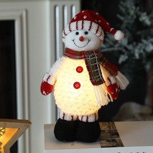 Leuchtende Weihnachts-Schneemann-Puppe mit roter Strickmütze und Schal auf Büchern