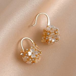 Elegant gold flower basket hoop earrings with white acrylic petals and sparkling crystals