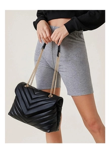 Detailed view of black quilted faux leather crossbody bag with golden chain strap