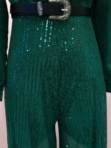 Detailed shot of dark green sequin fabric with a black belt and vintage metal buckle