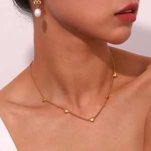 Close-up of a 18K gold plated necklace with five heart charms worn by a model