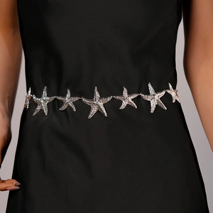 Detailed view of a silver starfish waist chain styled on a minimalist black dress