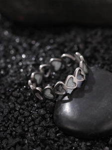 Macro detail of silver stainless steel ring with hollow heart design on a grey stone