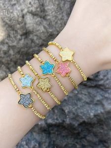 Close-up of adjustable star bracelets in gold with colorful glitter star pendants