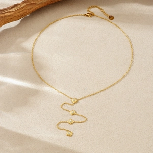 Gold plated stainless steel Y-necklace with four sparkling sun pendants on beige sand