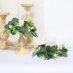 Close-up of eucalyptus wreath with white berries around a vintage wooden candle holder