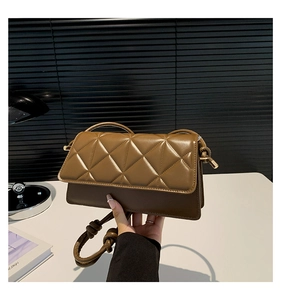 Détail du sac carré matelassé marron avec bandoulière nouée et finitions métalliques dorées