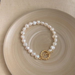 Close-up of white Baroque pearl bracelet with gold OT toggle clasp on a ceramic tray