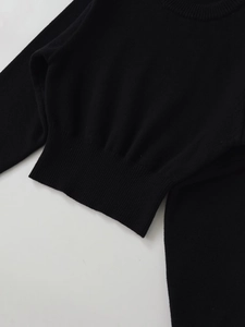 Close-up of black crew neck knit sweater with fine ribbing on cuffs and hemline