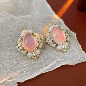 Close-up of vintage gold earrings with pink oval stones and crystal detailing