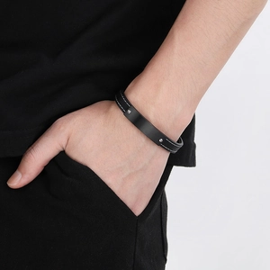 Detailed close-up of a black leather bracelet with matte black stainless steel plate