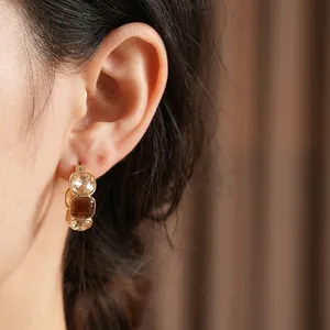 Vintage gold U-shaped earrings with champagne and amber gemstones on model ear