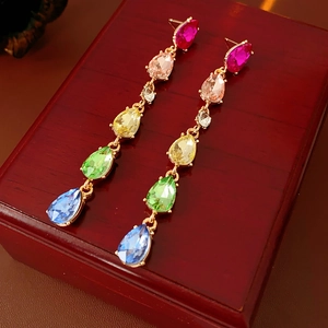 Close-up of colorful crystal teardrop tassel earrings on a vintage wood jewelry box