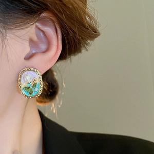 Close-up of vintage flower earrings with tulip relief, faux pearls and green enamel inlay