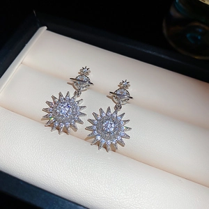 Macro detail of silver starburst earrings featuring zircon stones on white leather