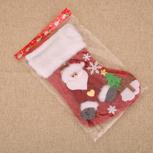 Macro shot of red plush Santa stocking with 3D figurines in transparent retail packaging