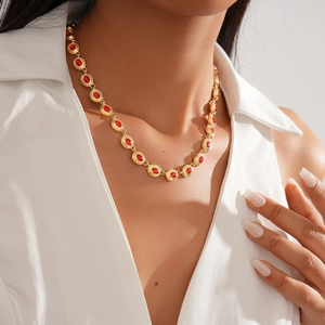 Detail of vintage gold necklace featuring elegant red round gemstones on a model