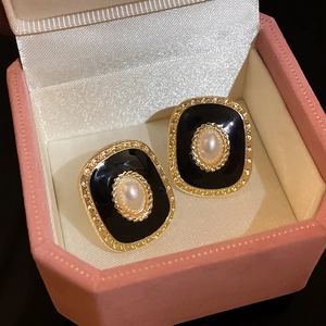 Détail de boucles d'oreilles émaillées vintage avec dorure et perle dans un écrin à bijoux