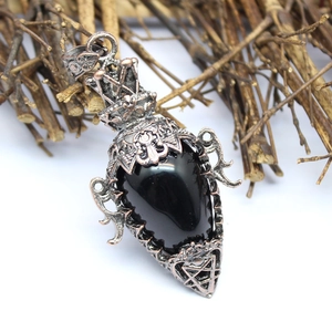 Macro view of gothic copper pendant necklace featuring black stone and filigree
